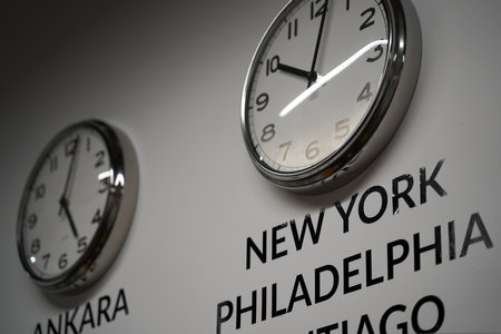 Many wall clocks on the white wall of business office showing time of different cities of the worldの写真素材