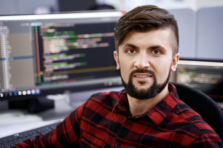 Computer programmer developer working in IT office, sitting at desk and coding, working on a project...