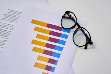 Stylish eyeglasses and colorful chart on the white work table. Business concept.の写真素材