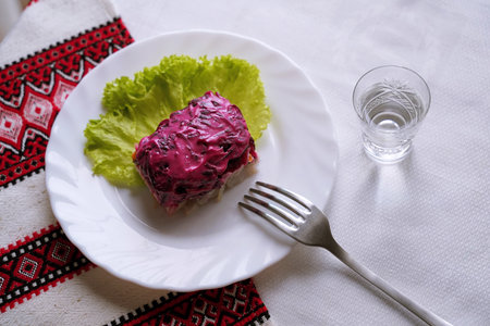 Dressed herring salad with a glass of horilka. Traditional Ukrainian food.の写真素材