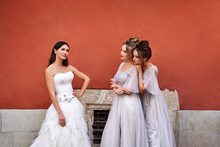 Beautiful bride and bridesmaids in gorgeous elegant stylish light grey silver floor length dresses in old beautiful European city having fun on a wedding day.の写真素材