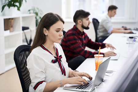 People working in modern IT office. Group of young and experienced programmers and software developers sitting at desks working on computers. Team at work. High quality image.の写真素材