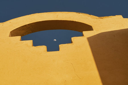 Daytime moon visible through a decorative window in an old Arabic style buildingの写真素材