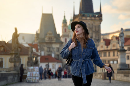 Female traveller tourist on the Charles Bridge in Prague, Czezh Repubic. Stylish beautiful young woman earing black hat. Elegant retro lady fine art portrait.の写真素材