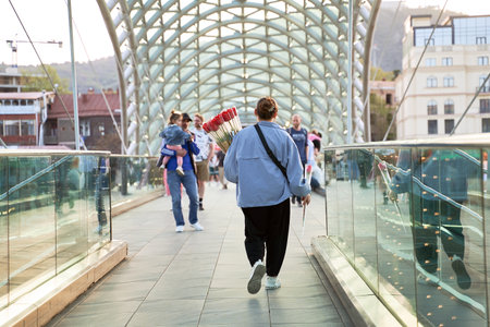 Tulip flower vendor crossing the famous Bridge of Peace over the Kura River in Tbilisi Georgiaのeditorial素材