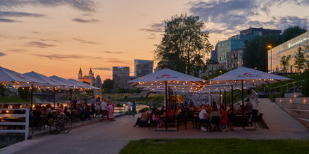 Night life in Vilnius. People relaxing in an evening cafe on the bank of the Neris river with Central Business District aka Vilnius CBD on backgroundのeditorial素材