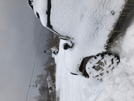Snow covered off-road vehicle SUV car parked outdoor on a winter ski slopeの写真素材