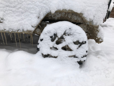 Rear wheel of a snow covered off-road vehicle SUV car parked outdoor on a winter ski slopeの写真素材