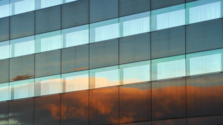 Evening clouds reflected in the modern building windows in a city backgroundの写真素材