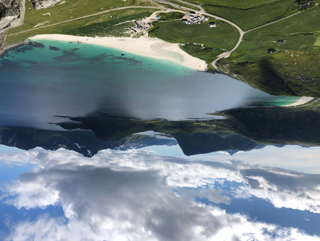 Aerial view of alpine lake with crystal clear water and reflection on the surface.