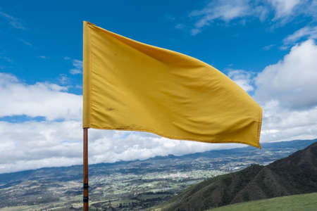 Close up attention yellow flag on blue sky over a mountainの写真素材