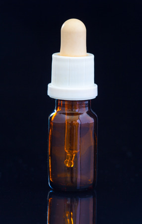 Dropper bottle with pipette on black backgroundの写真素材