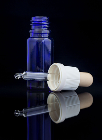 Dropper blue bottle with pipette on black backgroundの写真素材