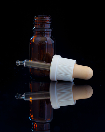 Dropper bottle with pipette on black backgroundの写真素材