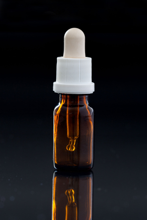 Dropper bottle with pipette on black backgroundの写真素材