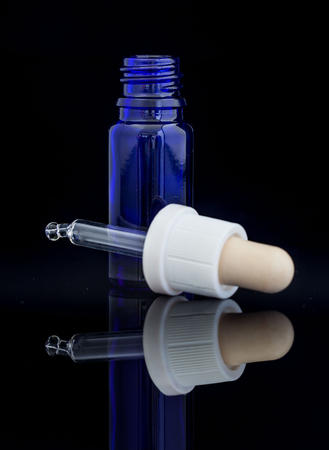 Dropper blue bottle with pipette on black backgroundの写真素材