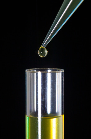 Laboratory pipette with a drop of substance over test tubesの写真素材