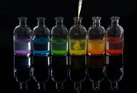 Apothecary, laboratory bottles with colored liquid and pipette with reflectionの写真素材