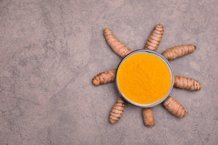 Curcuma powder and roots on a brown textured