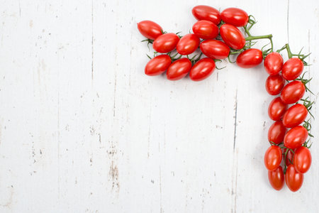Fresh red cherry tomatoes on a white shabby background, empty space for text