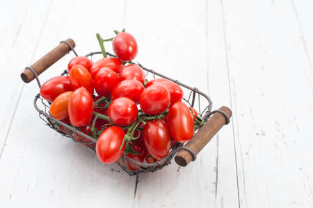 Fresh red cherry tomatoes on a white shabby background, empty space for textの写真素材