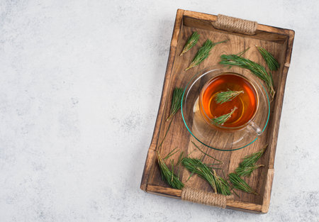 Pine needle tea in a cup on a white textured background, empty copy space for text, hot drink
