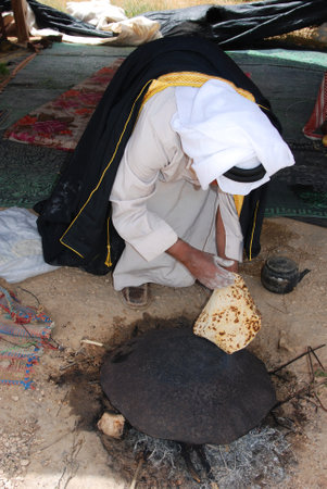 Bedouin in the Negev desert in Israel, traditional baking of breadin a tent, father and son eating a typical bedouin dish, tribal life, islamic cultureのeditorial素材