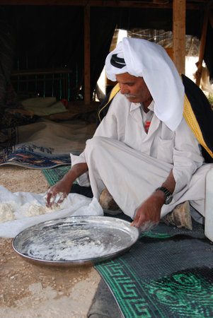 Bedouin in the Negev desert in Israel, traditional baking of breadin a tent, father and son eating a typical bedouin dish, tribal life, islamic cultureのeditorial素材