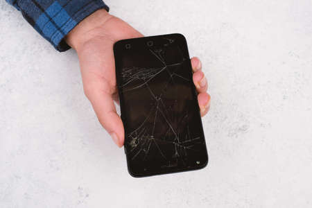 Smartphone with a broken display in the hands of a teenagerの写真素材