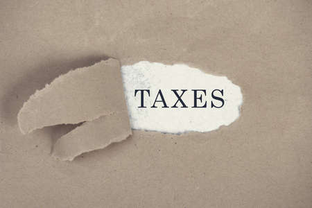 The word ttaxes is standing ona white background, ripped textured paperの写真素材