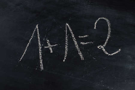 math exercise of first grade is standing on a blackboard, handwritten with white chalkの写真素材