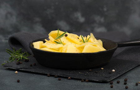 Potatoes in a pan with rosmarine, pepper and olive oilの写真素材