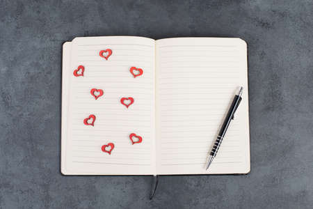 Empty notebook with wooden hearts and a penの写真素材