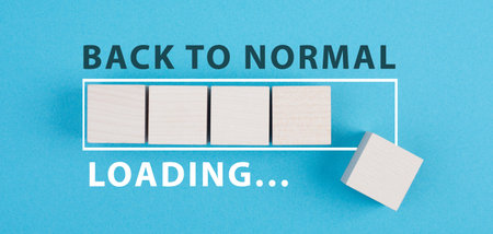 Back to normal is standing on a blue background, loading bar with wooden cubes, life after covid-19の写真素材