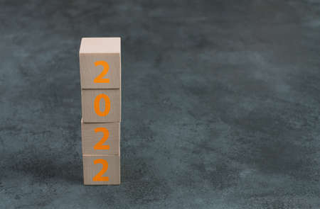 The year 2022 is standing on wooden cubes, dark background, empty copy spaceの写真素材