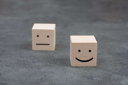 Wooden cubes with a happyand a sad face on a dark background, symbolの写真素材