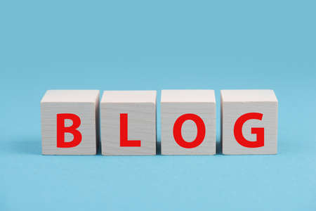 The word blog is standing in red colored letters on wooden cubes, blue backgroundの写真素材