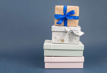 Gift boxes in different sizes and colors in front of a dark blue background, copy spaceの写真素材