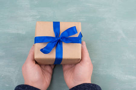 Holding a gift box in the hands, blue colored backgroundの写真素材