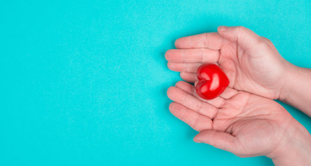 Woman is holding a red heart in her hand, blue colored background, copy space