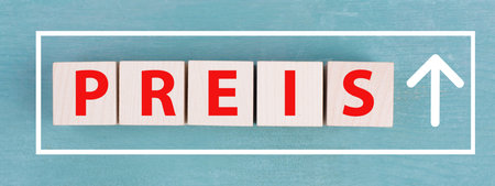 The word price is standing in German language on wooden cubes, arrow is going upの写真素材
