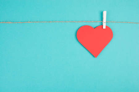 A heart hanging on a clothing line, blue colored background, empty copy space, symbol of love, valintine greeting cardの写真素材