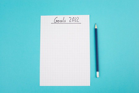 Empty paper with goals 2022, copy space for text, pen, blue colored background, business concept,...
