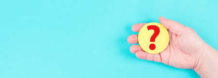 Woman holds a red question mark in her hand, blue background, copy space for text, finding answersの写真素材