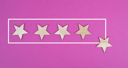 Five stars on a pink colored background, hand put the last star in the row, rating, giving feedbackの写真素材