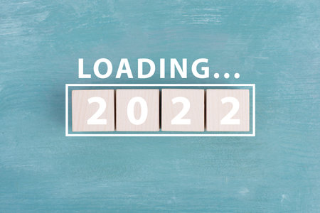 2022 is standing in white colored letters on wooden cubes, the word loading is standing above, blue...