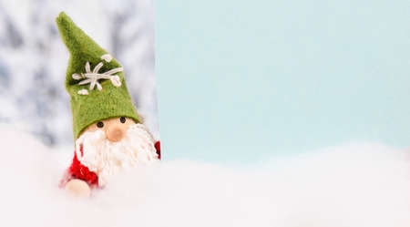 Little cute christmas gnome standing in the snow, forest, festive greeting card, copy space, wintertimeの写真素材