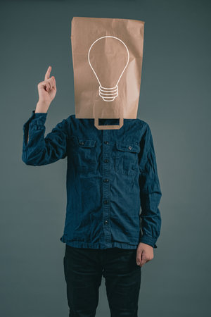 Young man with a paper bag on his head, light bulb, having an idea, start upの写真素材