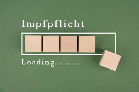 Mandatory vaccination is standing in German language on a green background, loading bar, hand puts last cubeの写真素材