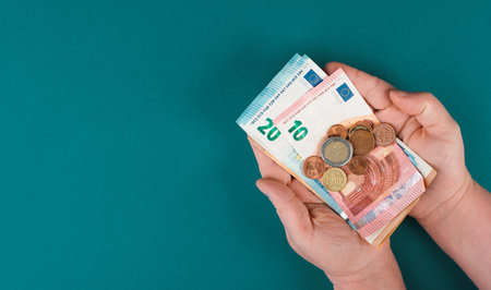 Holding Euro banknotes and coins in the hands, counting money, saving income, copy space for text